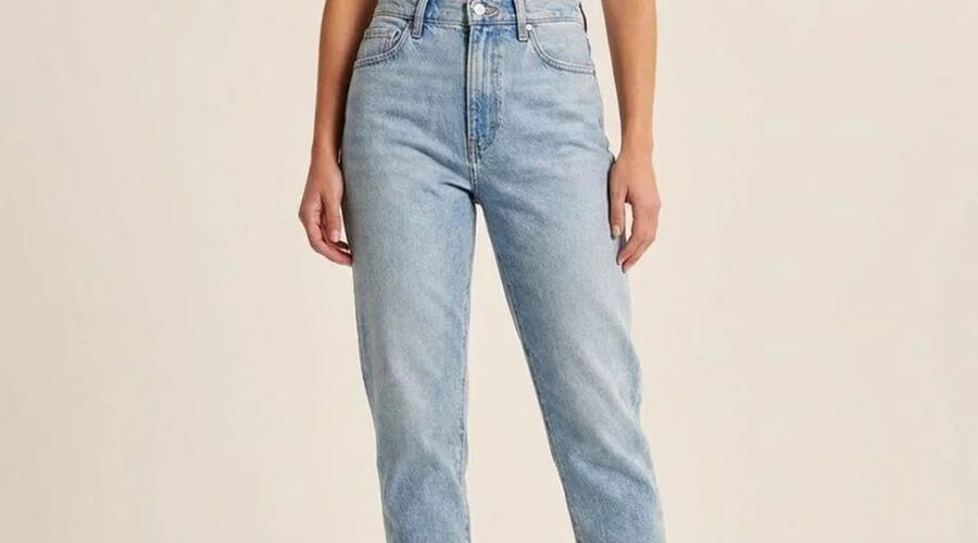 Model in light-wash mom jeans with a high waist and tapered ankle