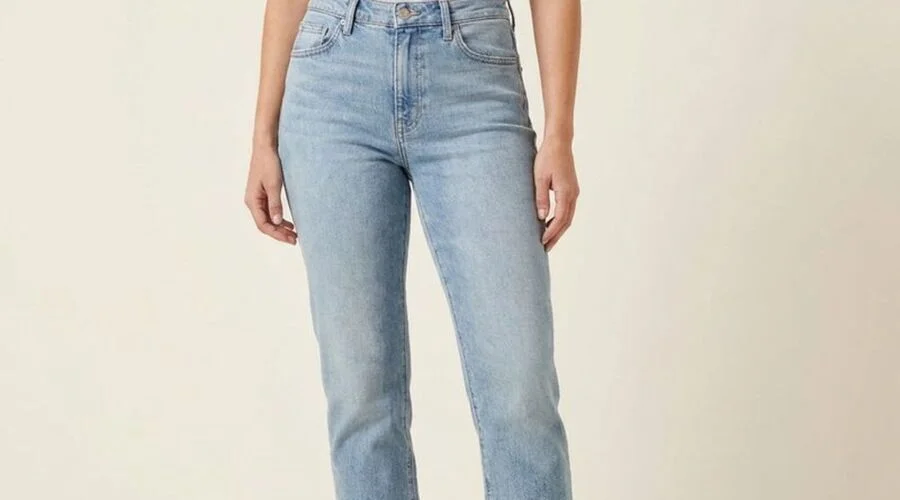 Model wearing light-wash straight jeans with a white shirt and tan loafers