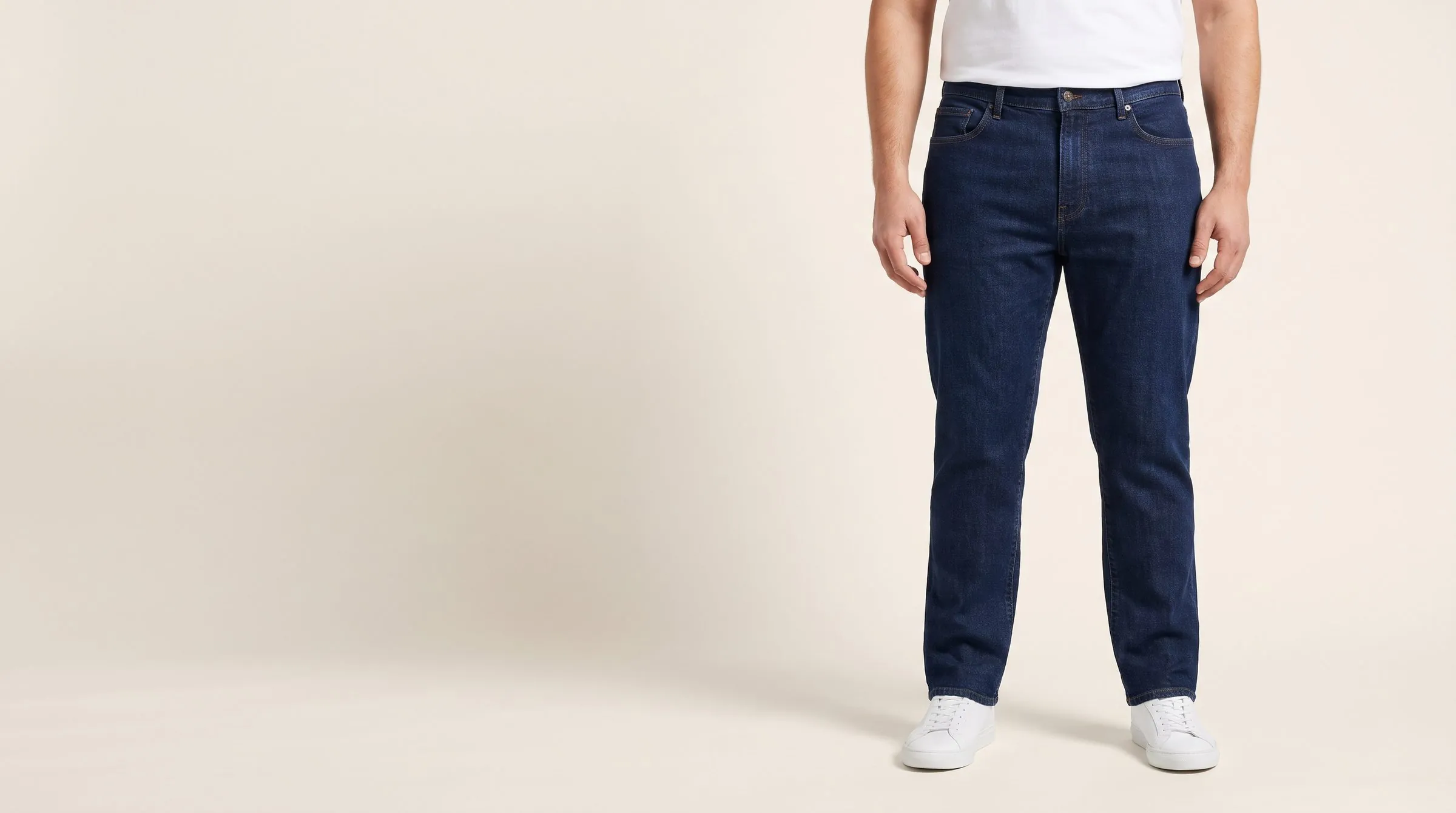 Men's straight-leg jeans laid flat with a tailor's level and tape along the waistband