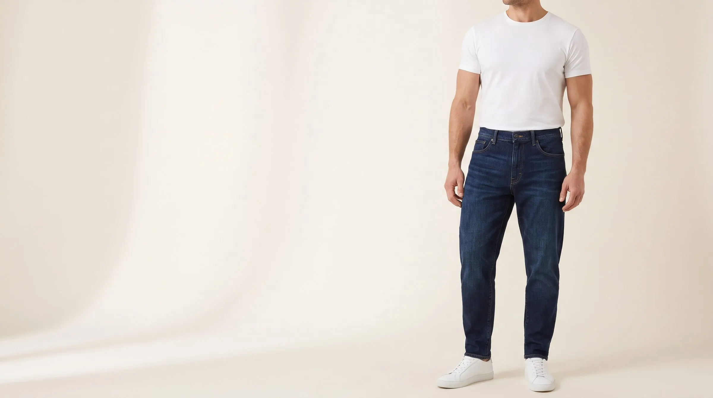 Men's mid-wash straight and tapered jeans on a cutting table with a tape across a narrow waistband