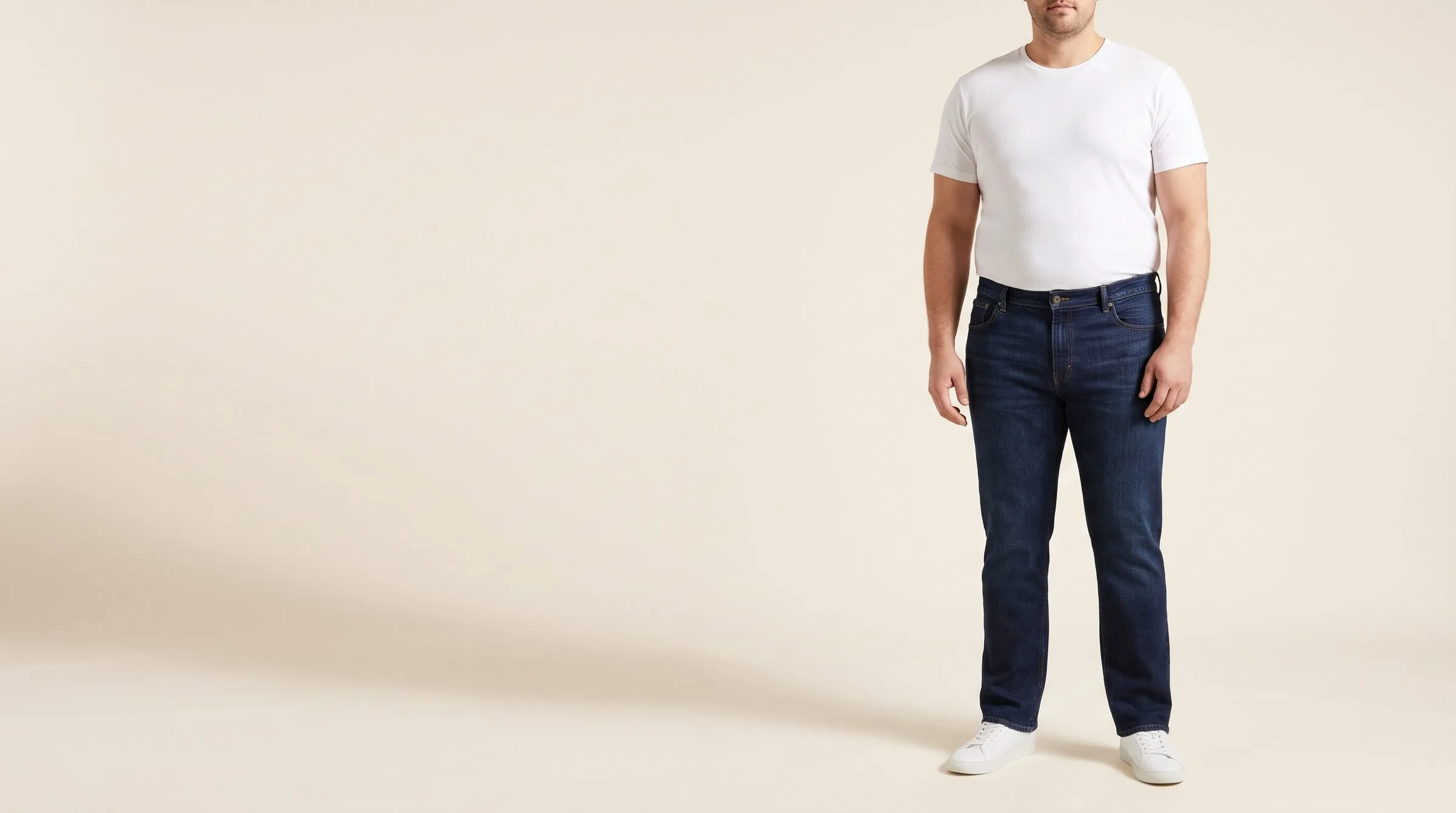 Dark straight-leg men's jeans with a high rise on a cutting table, the tape measuring the front rise