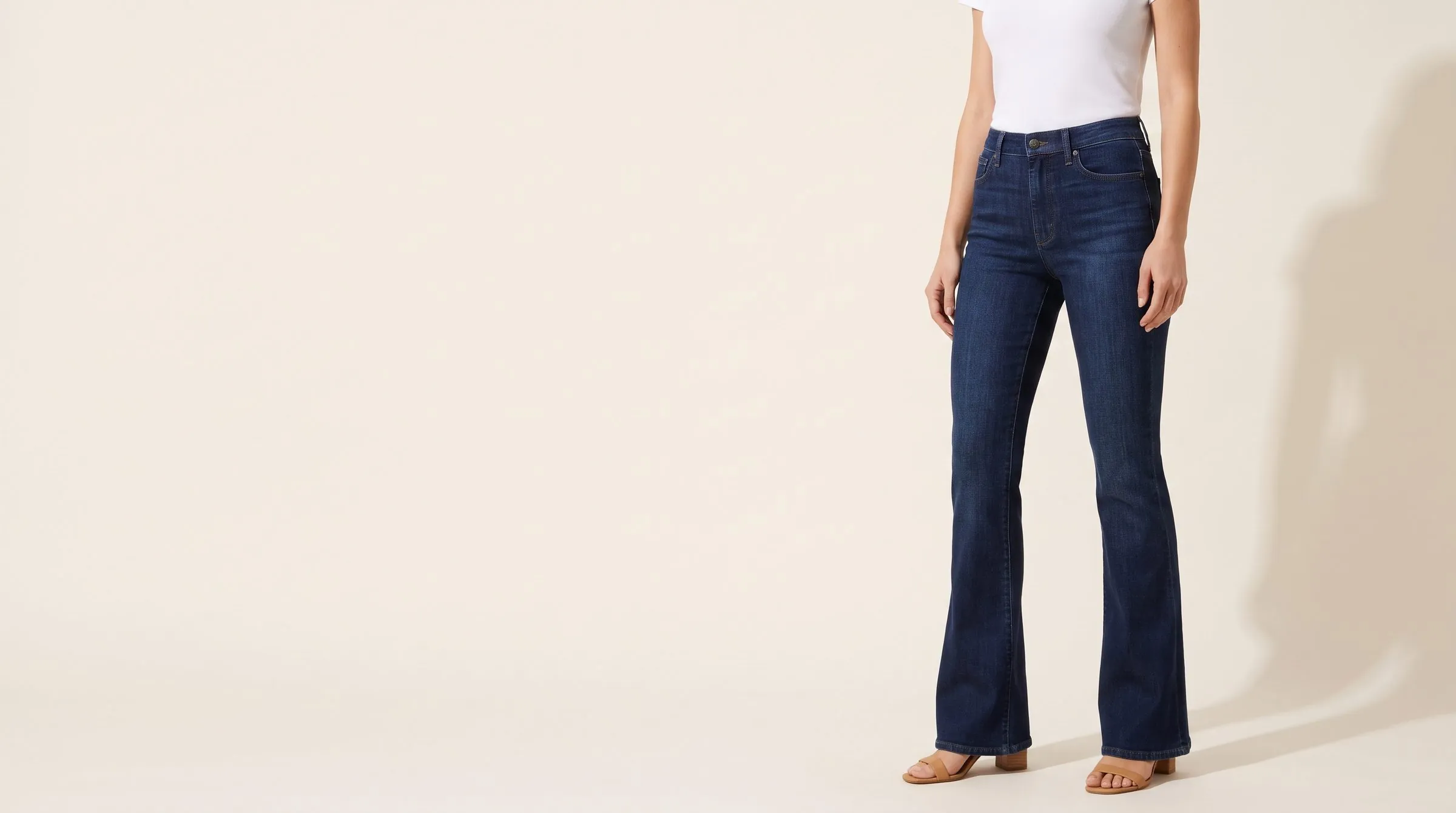 Flare, barrel and mom jeans laid side by side on a cutting table with a tape measure and chalked pattern paper