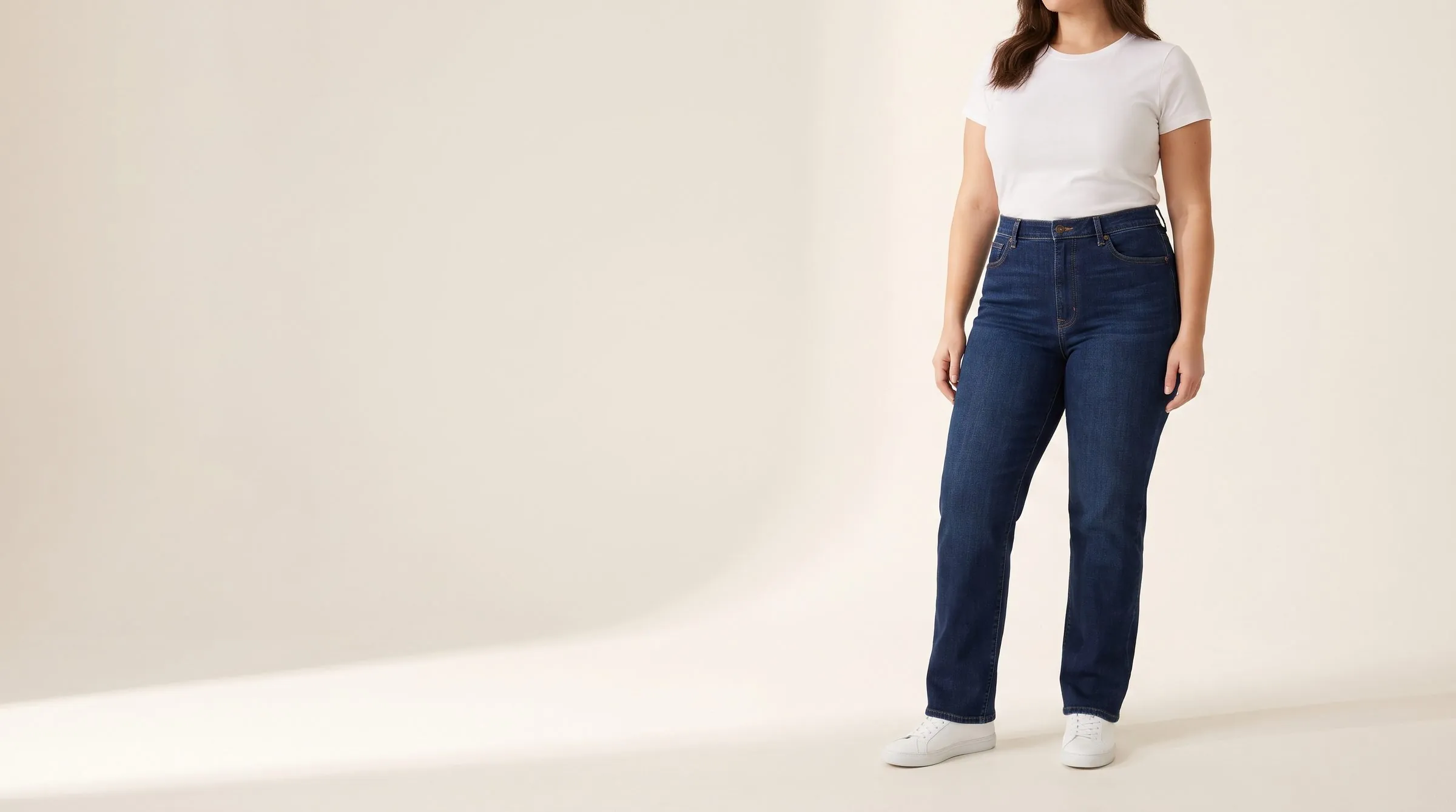 Straight, wide leg and flare jeans fanned out on a table, the hems spread wide, a tape measure across the top
