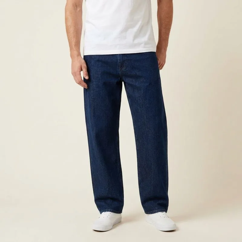 Man wearing dark-wash relaxed jeans with a plain tee and sneakers